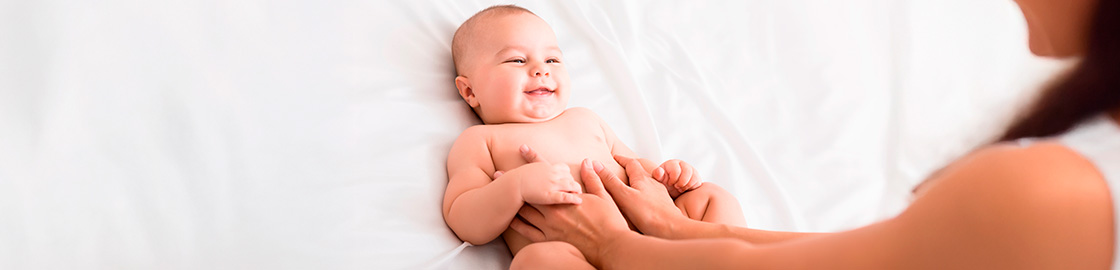 foto de bebé sobre una cama recibiendo un masaje de parte de su mamá.