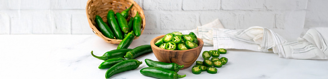foto de una mesa con chiles jalapeños enteros y cortados encima.