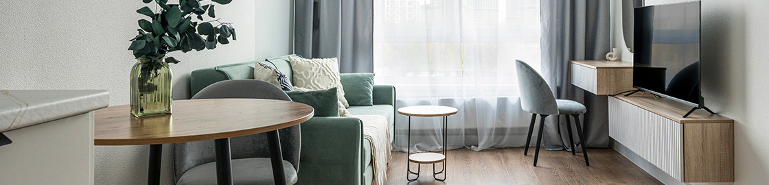 Foto de la pequeña sala de un departamento con un sillón, mueble para la televisión y una pequeña mesa.